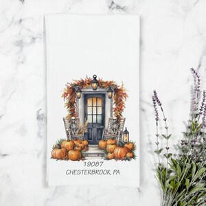 May include: White kitchen towel with a watercolor illustration of a front door decorated for Halloween. The design includes pumpkins, skeletons in rocking chairs, and the text "19087 CHESTERBROOK, PA."