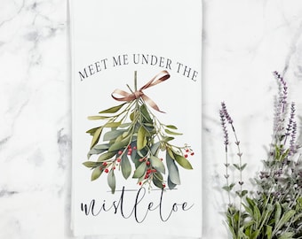May include: White kitchen towel with a green and red mistletoe illustration and the text "Meet me under the mistletoe".
