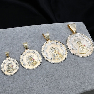 May include: Seven gold and silver pendants with religious imagery. The pendants are round and feature a detailed design of a woman holding a baby. The pendants are of varying sizes and are arranged in a row on a gray surface.