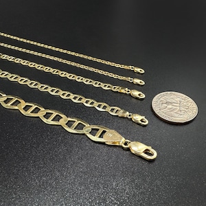 Four gold mariner chains of increasing thickness laid horizontally next to a US quarter coin for scale.