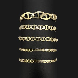Five different widths of gold mariner chain bracelets wrapped around a dark vertical cylinder display.