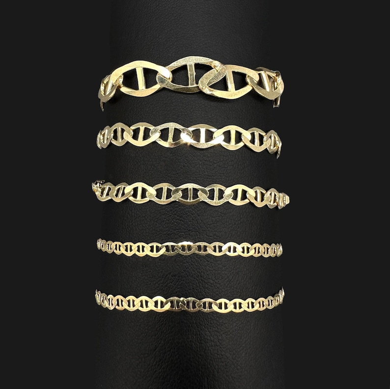 Five different widths of gold mariner chain bracelets wrapped around a dark vertical cylinder display.
