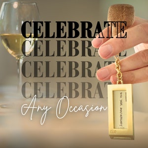 Op de afbeelding: Een gouden flessenstop met een gouden ketting en een klein rechthoekig label met de tekst "occasion 40th year anniversary! clic". De flessenstop bevindt zich in een hand, en de achtergrond is een wazig beeld van een glas witte wijn.