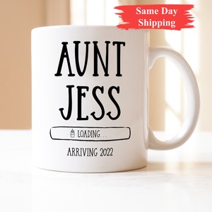 May include: White ceramic mug with black text that reads "Aunt Jess" and a loading bar with a baby bottle icon. The text below the loading bar reads "Arriving 2022".