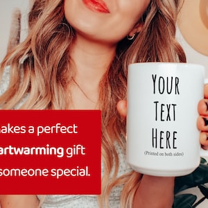 Peut inclure: Mug en c&eacute;ramique blanche avec le texte "YOUR TEXT HERE" imprim&eacute; en noir. La tasse a une grande anse et est tenue par une personne. Le texte "Makes a perfect heartwarming gift for someone special" est sur fond rouge.