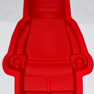 May include: Red silicone mold shaped like a Lego minifigure. The mold has a simple design with a head, torso, arms, and legs.