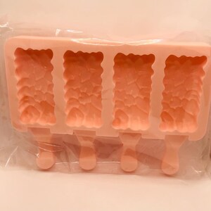 以下が含まれることがあります： ピンクのシリコン製のアイスキャンディー型。4つの個別の型があり、それぞれにテクスチャ加工が施され、スティックが付いています。