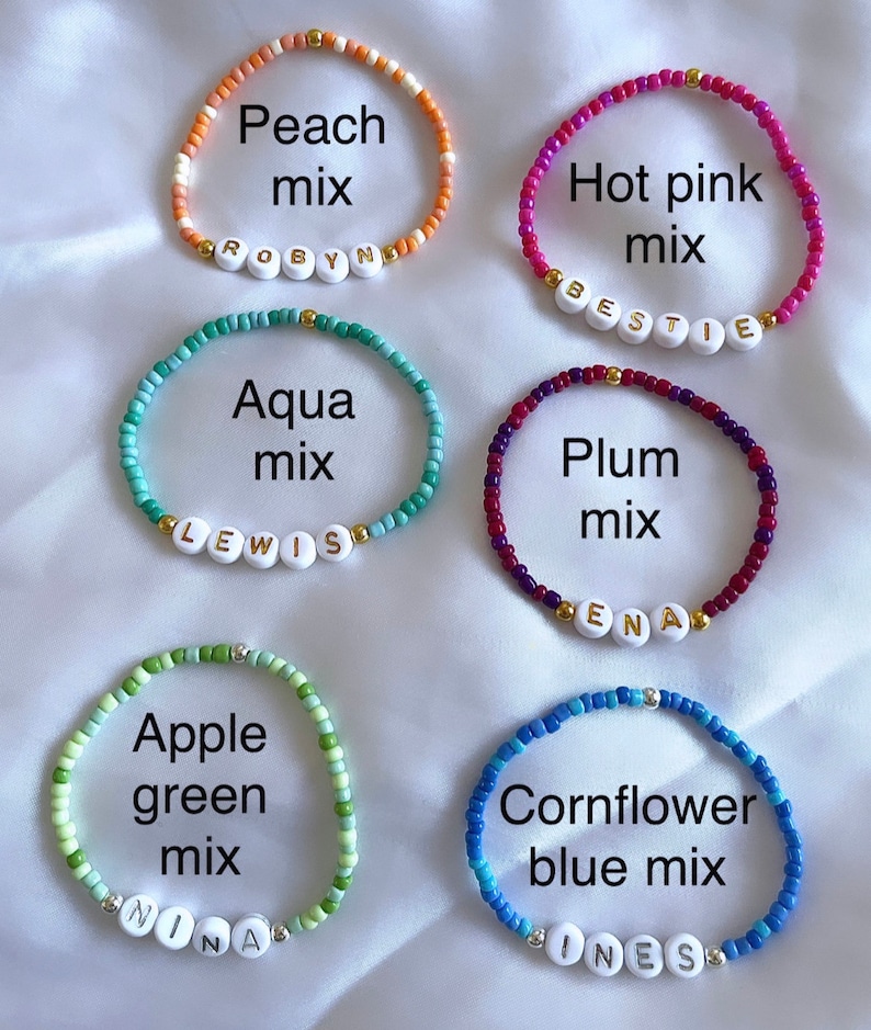 May include: Six beaded bracelets with different color combinations and names spelled out on each bracelet. The bracelets are peach mix with the name "ROBYN", hot pink mix with the name "BESTIE", aqua mix with the name "LEWIS", plum mix with the name "ENA", apple green mix with the name "NINA", and cornflower blue mix with the name "INESS".
