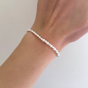 May include: A silver beaded bracelet with small, round beads.