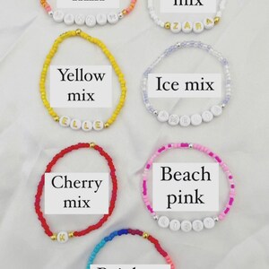 May include: Six colorful beaded bracelets with white letter beads spelling out names. The bracelets are arranged in two rows of three. The top row includes coral, frost, and yellow mix bracelets. The bottom row includes ice mix, cherry mix, and beach pink bracelets. The bottom row also includes a rainbow bracelet.