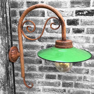 May include: A rusty metal wall-mounted light fixture with a green glass shade and a clear glass bulb. The fixture has a decorative scroll design.