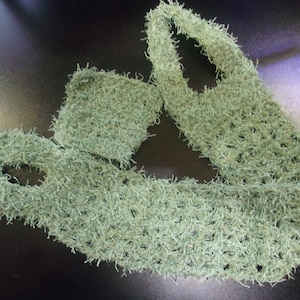Pode incluir: Uma echarpe de crochê verde com uma textura felpuda. A echarpe é feita de um fio macio e leve, ideal para adicionar um toque de calor e estilo a qualquer roupa.