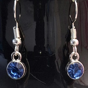 May include: A pair of silver dangle earrings with blue crystal stones.