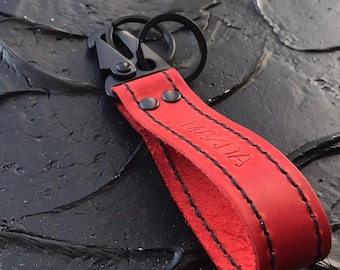 赤いレザーのマツダキーホルダーと黒いカラビナ、カーアクセサリー