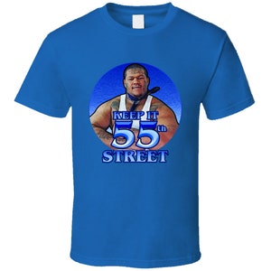 May include: A blue t-shirt featuring a circular graphic of a man wearing a blue bandana with the text "Keep It 55th Street".