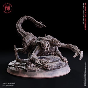 May include: A detailed miniature figure of a Shadowherder, a monstrous creature with a scorpion-like tail and multiple limbs. The figure is dark brown and rests on a 75 mm base. The text "GRIMOIRES OF MADNESS" is visible.