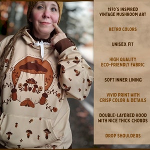 May include: A beige hooded sweatshirt with a vintage mushroom illustration in brown and white. The sweatshirt has a double-layered hood with thick cords, drop shoulders, and a soft inner lining. The text "1970's INSPIRED VINTAGE MUSHROOM ART" is printed on the right side of the image.