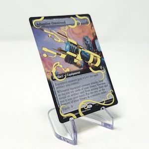 Könnte beinhalten: Eine schwarze und goldene Magic: The Gathering Karte mit dem Text "Adaptive Omnitool" und "Artifact - Equipment". Die Karte zeigt eine Illustration einer futuristischen Waffe.