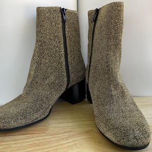 May include: A pair of gold glitter ankle boots with black zippers and heels.