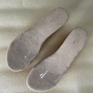 May include: Two pairs of beige insoles with the text "URBAN OUTFITTERS" printed on them.