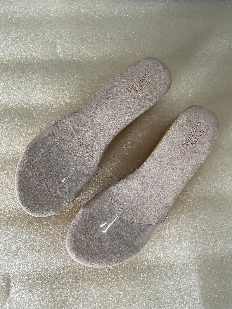 May include: Two pairs of beige insoles with the text "URBAN OUTFITTERS" printed on them.