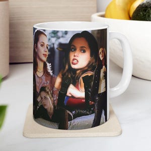 May include: White ceramic mug with a collage of images of women. The images show various poses and settings. The mug has a white handle and interior. The mug is on a beige coaster.
