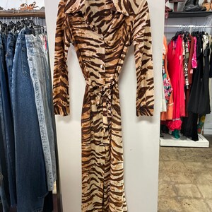 May include: A long-sleeved brown and white tiger print dress with a button-up front and a tie belt.
