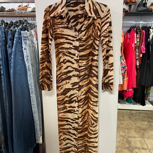 May include: A long-sleeved, brown and beige tiger print dress with a button-up front.