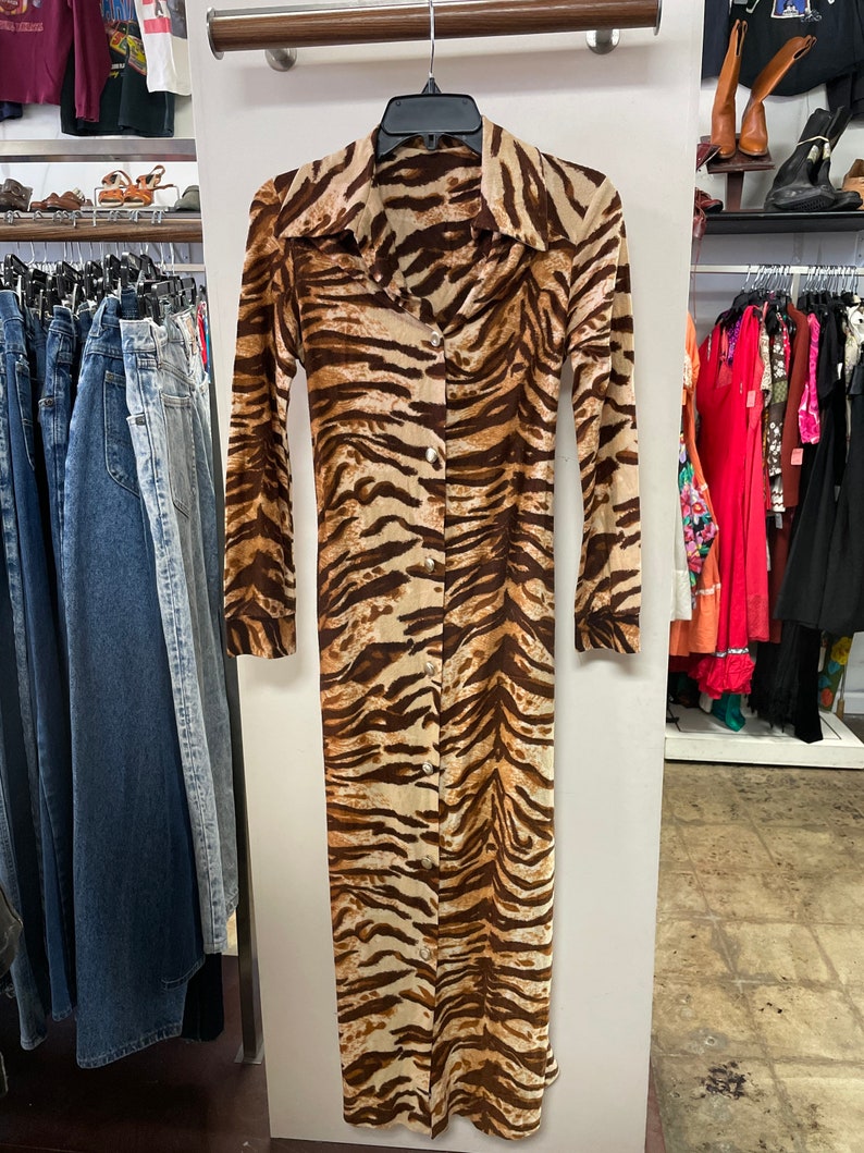 May include: A long-sleeved, brown and beige tiger print dress with a button-up front.