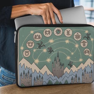 May include: A rectangular laptop sleeve featuring a sage green background with a celestial design of stars, flying dragons, and circular icons. The lower portion displays a landscape of light blue mountains and gray stone castles with pointed towers.