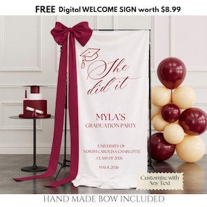 May include: A graduation banner with the text "She did it" and details. A burgundy bow and streamers are at the top. A cake and balloons in burgundy and cream are also present. The banner reads "MYLA'S GRADUATION PARTY".