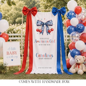 Op de afbeelding: Een babyborrel display met rode, witte en blauwe ballonnen, een bord en een banner. De banner leest "Our Little American Girl is on the Way" met een strik en kersen ontwerp. Een teddybeer zit in de buurt van de ballonnen. Het bord zegt "A little BABY is on the way."