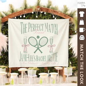 May include: A white banner with green tennis rackets and pink champagne glasses. The banner reads "The Perfect Match Found Jamie-Lee's Bachelorette New Orleans - Nov 22, 2021".