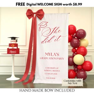 May include: A graduation party scene with a white banner reading "She did it" and "Myla's Graduation Party." A red bow and ribbons are attached to the banner. A three-tiered cake with a graduation cap sits on a small table. Balloons in red, burgundy, and cream colours are on the right.