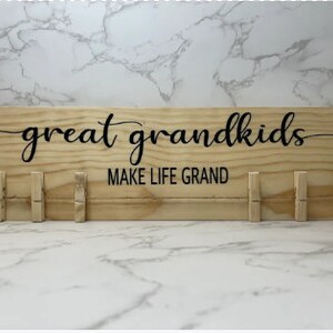 May include: A wooden sign with the text "great grandkids make life grand" in black lettering. The sign has 10 wooden clothespins attached to the bottom.