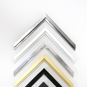 Könnte beinhalten: Nahaufnahme von sechs verschiedenen Bilderrahmenecken, die verschiedene Oberflächen zeigen. Die Rahmen sind in Pyramidenform angeordnet, wobei der silberne Rahmen oben und der schwarze Rahmen unten ist. Die anderen Rahmen sind silber, gold und schwarz.