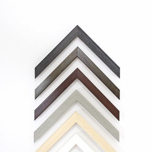 May include: A set of seven picture frames in various colours, including white, beige, grey, brown, and black. The frames are arranged in a pyramid shape, with the largest frame at the top and the smallest frame at the bottom.