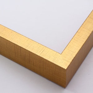 May include: A gold picture frame with a textured finish. The frame is made of wood and has a simple, elegant design.