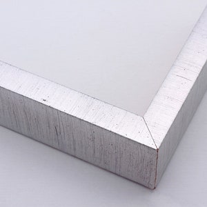 May include: Close-up of a silver picture frame with a textured finish. The frame has a beveled edge and a subtle sheen.