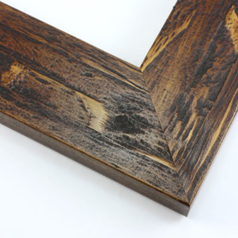 May include: Close-up of a corner of a rustic wooden picture frame. The frame has a distressed finish with shades of brown, gray, and tan, showcasing the natural wood grain. The corner is joined at a 45-degree angle.