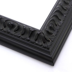 May include: A black picture frame with a decorative, ornate design. The frame has a wide, flat border and a raised, textured edge.