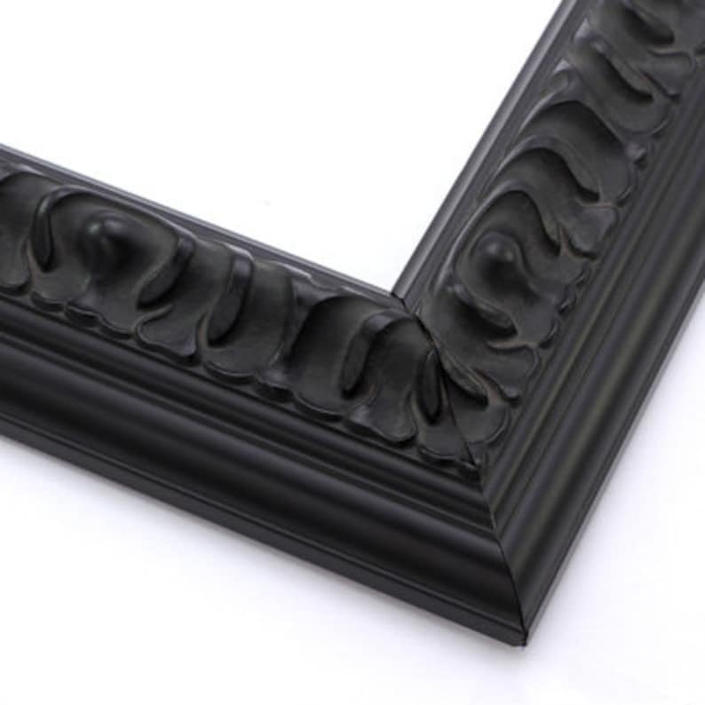 May include: A black picture frame with a decorative, ornate design. The frame has a wide, flat border and a raised, textured edge.