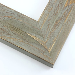 May include: Close-up of a corner of a wooden picture frame. The frame has a distressed, weathered appearance with a gray-blue finish and visible wood grain. The edges are dark brown.
