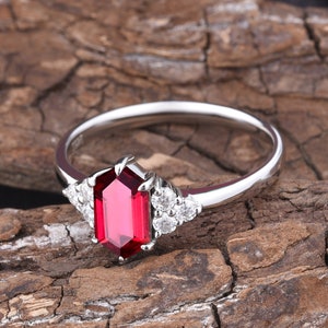 May include: A silver ring with a large, octagon-shaped ruby gemstone surrounded by smaller, round diamonds.