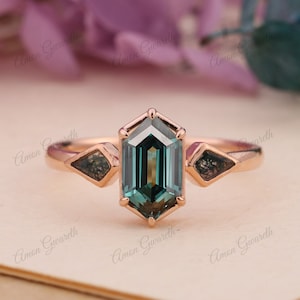 May include: A rose gold engagement ring with a teal green octagon-shaped gemstone. The ring has two smaller triangular gemstones on either side of the main stone.