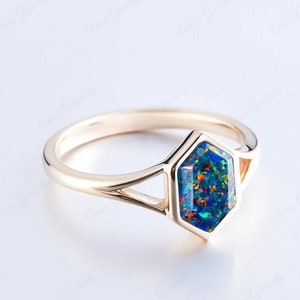May include: A gold ring with a hexagonal shaped blue opal gemstone. The ring has a split shank design.