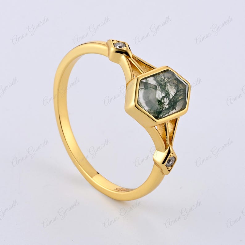 Puede incluir: Un anillo de oro con una piedra hexagonal de &aacute;gata verde musgo y dos peque&ntilde;as piedras de acento transparentes.