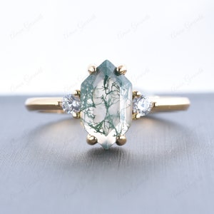Puede incluir: Un anillo de oro con una piedra preciosa de ágata verde musgo y dos piedras preciosas más pequeñas transparentes en la banda.