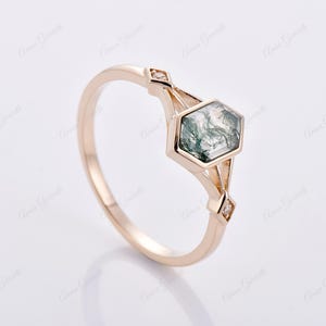 Puede incluir: Un anillo de oro con una piedra hexagonal de &aacute;gata verde musgo y dos peque&ntilde;os diamantes en la banda.