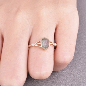 Puede incluir: Un anillo de oro con una piedra preciosa hexagonal verde y gris y dos peque&ntilde;os diamantes a cada lado.